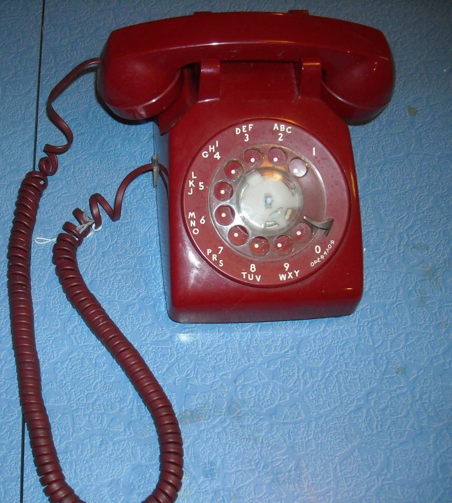 Vintage red rotary telephone photographed against a simple background